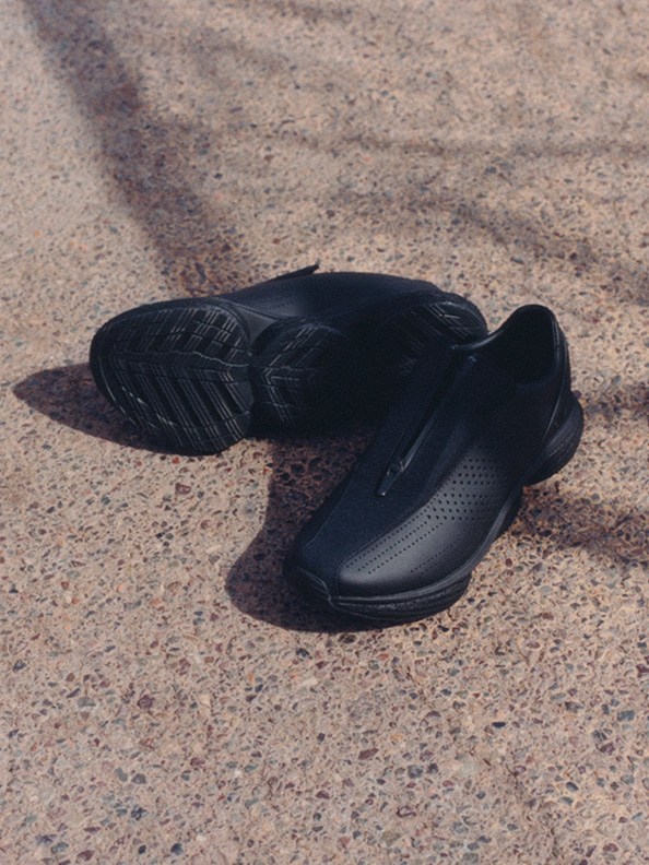 A pair of black athletic shoes rests on a textured concrete surface.