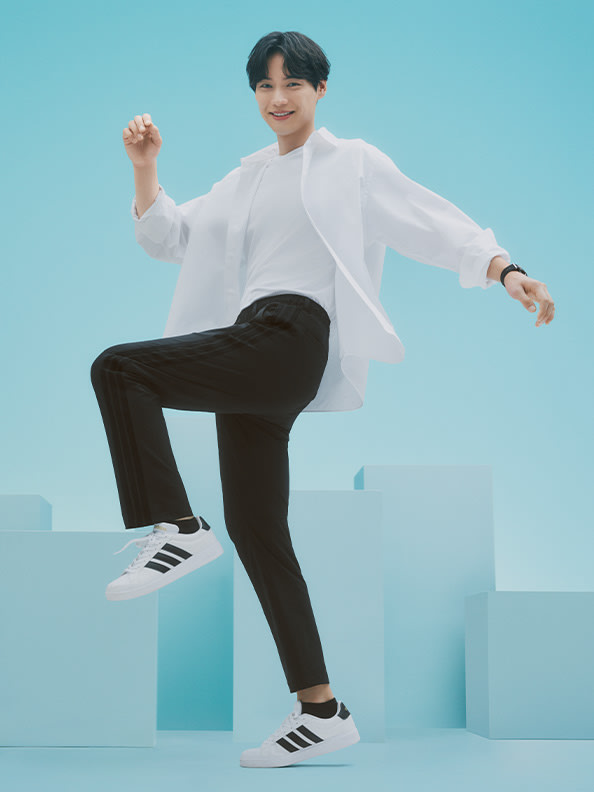 A person in a white shirt and black pants is standing on a platform against a blue background, with their arms raised in a dynamic pose.