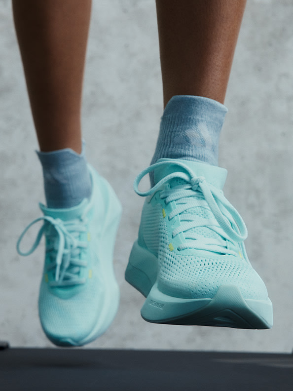 A pair of mint green athletic shoes with laces and a textured sole are prominently featured against a plain, light-colored background.