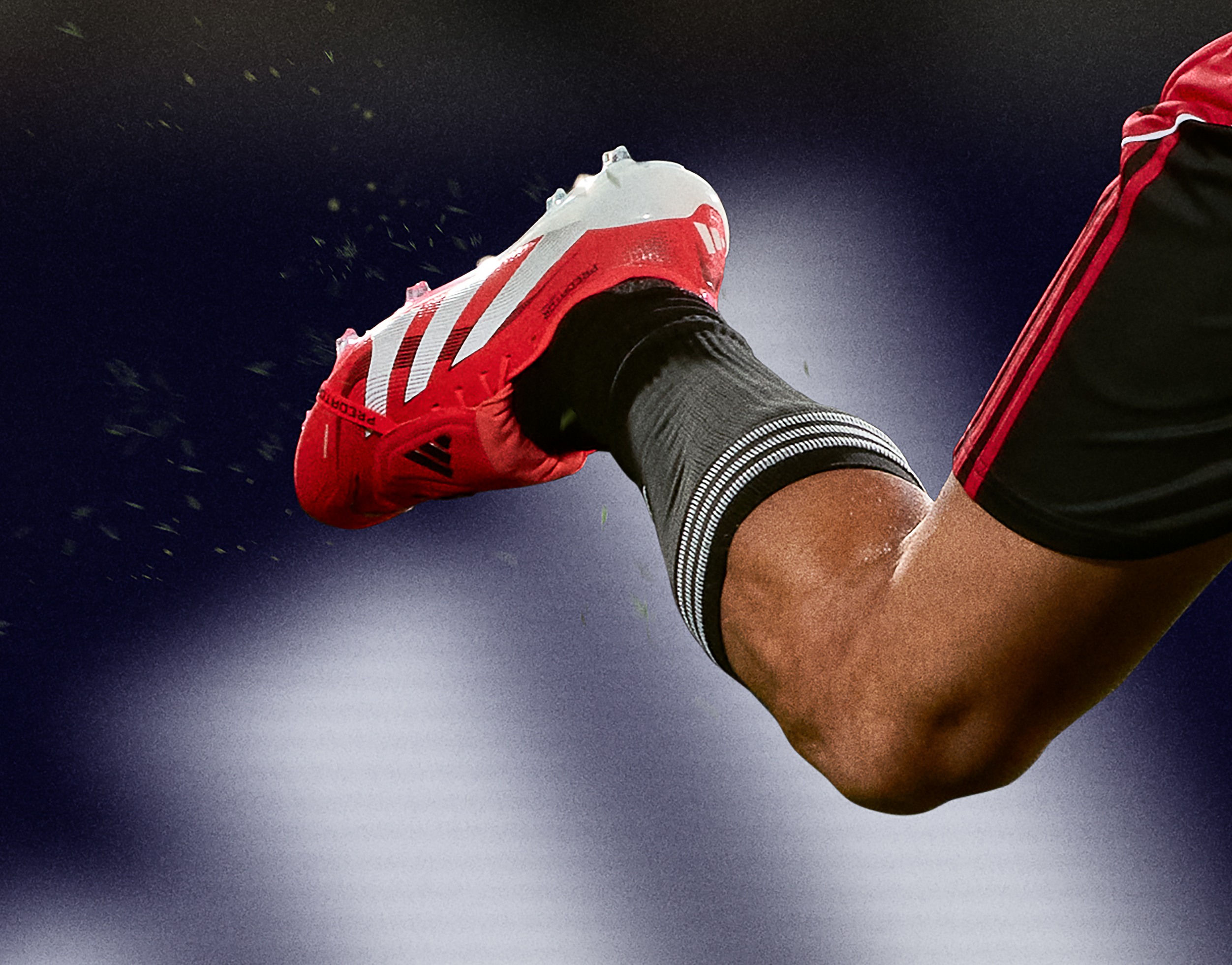A close-up view of a person's leg wearing a red and white athletic shoe, with a dark background and water droplets visible.
