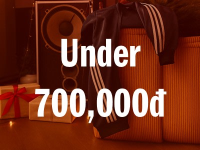 The image shows a large speaker system with the text "Under 700,000d" displayed prominently in the foreground, surrounded by various gift boxes in the background.