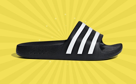 A black and white striped slide sandal against a vibrant yellow background with radiating lines.