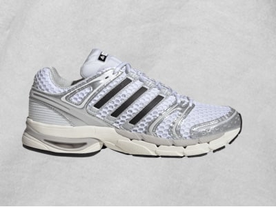 A white and gray athletic shoe with a mesh upper and distinctive stripes on a plain background.