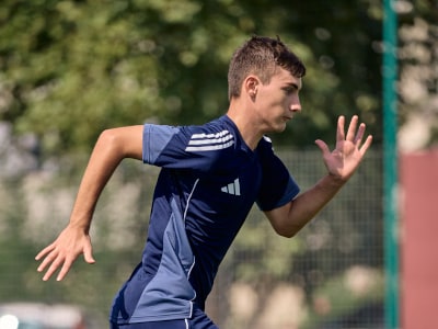 Bilden visar en närbild av en person som bär en färgglad, randig sportjacka med en synlig adidaslogga.