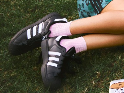 The image shows a person's feet wearing black-and-white athletic shoes on a grassy background.