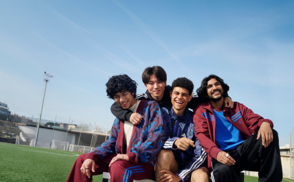 A person wearing adidas outdoor running gear, standing in front of a large, printed canvas depicting mountains and blue skies.
