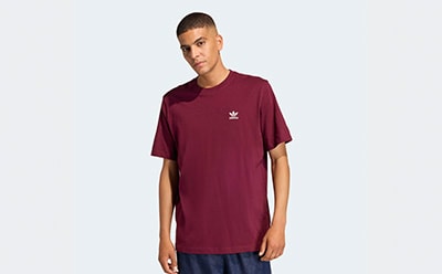 A young person wearing a burgundy t-shirt with the Adidas logo stands against a plain white background.