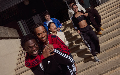 A group of young people, some smiling and others with serious expressions, are standing on a set of stairs in an urban setting.