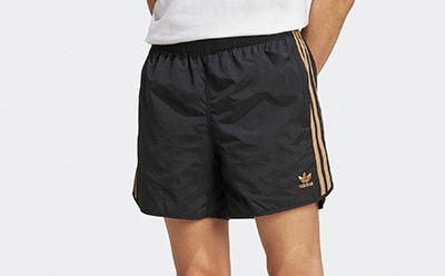 The image shows a pair of black athletic shorts with gold stripes on the sides, against a plain white background.