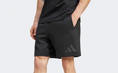 The image shows a close-up view of a person's lower body wearing black athletic shorts with the Adidas logo visible.