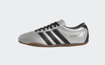 Une sneaker blanche et noire avec une semelle en gomme est représentée sur un fond blanc uni.