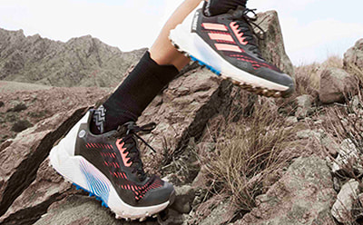 Close up of athlete’s foot wearing adidas Agravic trail running shoe while running outdoors.