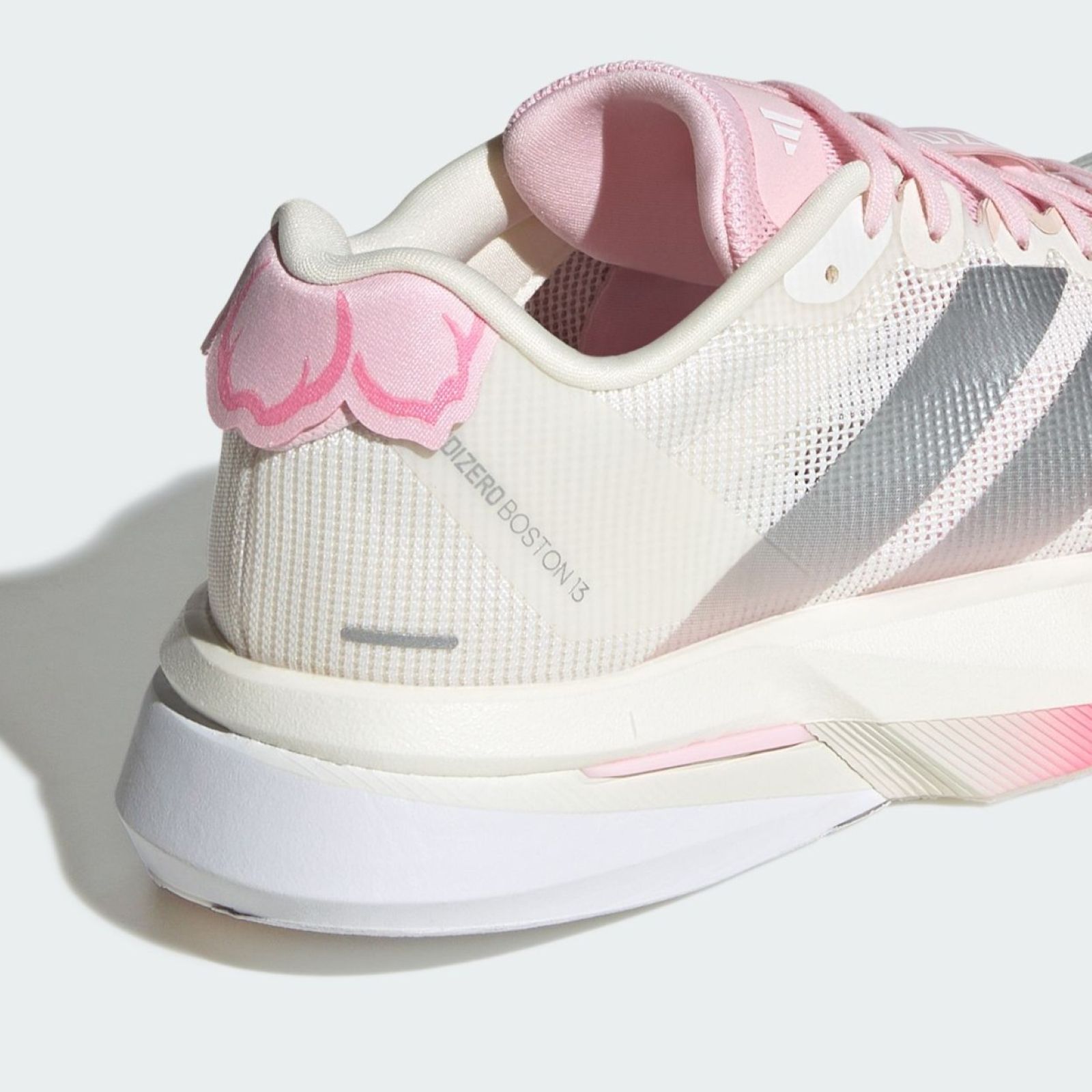 The image shows a pair of white and pink athletic shoes with a mesh upper and a thick sole. The shoes have a distinctive design with pink accents and appear to be a sports or running shoe model.