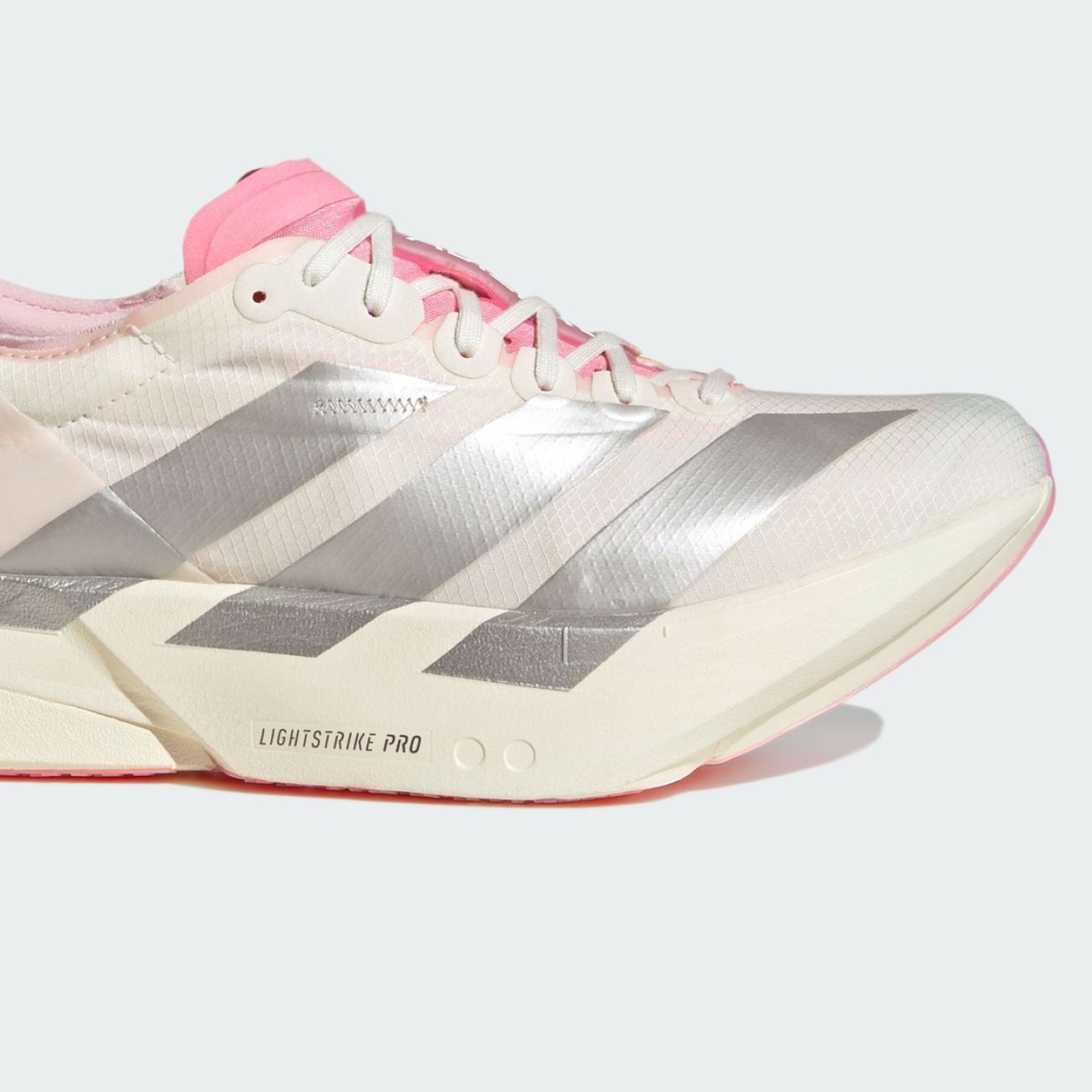 A pair of white and pink athletic shoes with distinctive silver stripes and a red sole, set against a plain background.