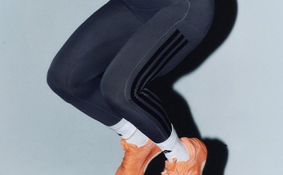 A close-up view of a person's legs wearing black leggings or tights, with the background appearing to be a light, neutral color.