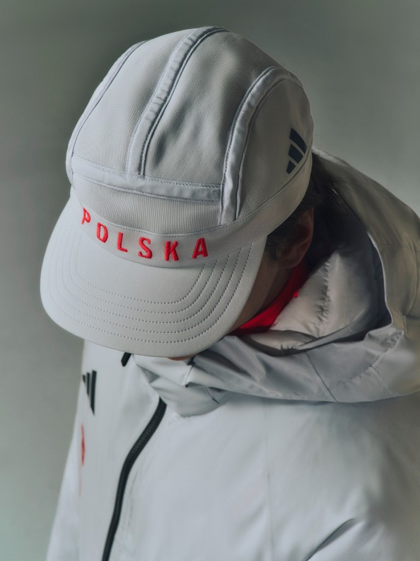 Szara czapka z czerwonym napisem "POLSKA" na przodzie, osadzona na białej kurtce zimowej.