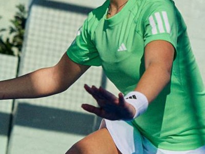 The image shows a person wearing a green sports jersey with white stripes, standing in front of a white background.