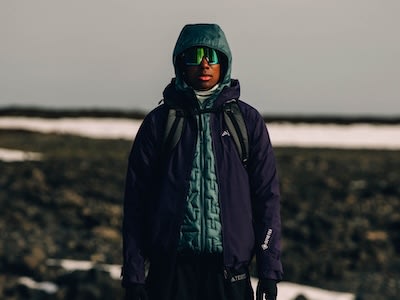 Una persona con una chaqueta oscura está de pie en un paisaje rural nevado.