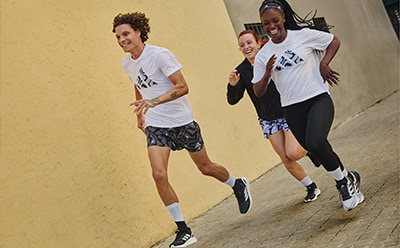 The image shows two people, a man and a woman, running together in an outdoor setting with a yellow wall in the background.