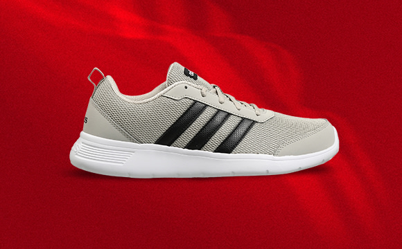 A pair of gray and black athletic shoes with a white sole sits on a vibrant red background.