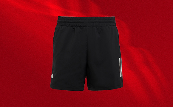 A pair of black athletic shorts with white stripes on a vibrant red background.