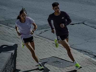 Two individuals, a man and a woman, are running on a paved path surrounded by a dark, gloomy environment.