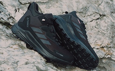 Para czarno-morskich butów sportowych osadzona na kamienistej, teksturowanej powierzchni.