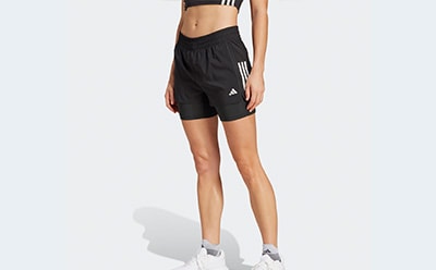 The image shows a person wearing black athletic shorts and sneakers, standing against a plain white background.