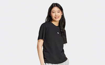 A young woman with long dark hair is smiling and wearing a black t-shirt against a plain white background.