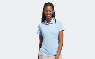 A smiling young woman wearing a light blue polo shirt stands against a plain white background.