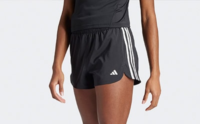 The image shows a pair of black athletic shorts with white stripes on the sides, worn by a person's lower body.