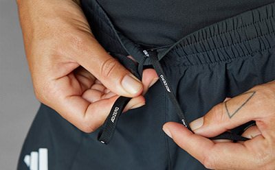 The image shows a person's hands zipping up a black jacket or garment.