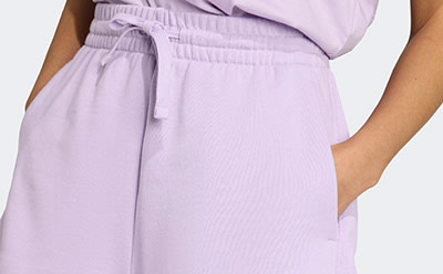 A close-up view of a person wearing a light purple, pleated dress with a drawstring waist, against a plain background.