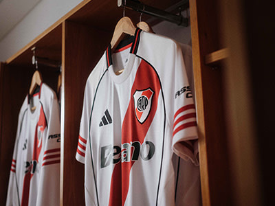 The image shows several white and red soccer jerseys hanging on a wooden rack, with the team name "River Plate" visible on the jerseys.