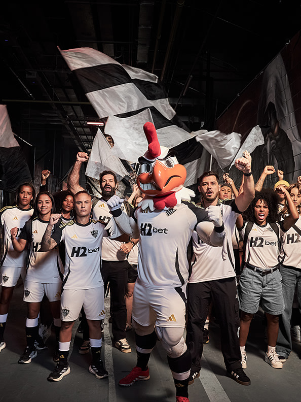 A group of people wearing white jerseys with the number "12" and holding up a large flag, celebrating together in what appears to be a sports or entertainment event.
