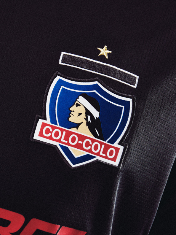 The image depicts the logo of the Colo-Colo football club, which features a shield-shaped emblem with a profile of a person wearing a hat against a dark background.