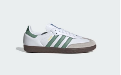 A white and green sneaker with a gum sole is displayed against a plain white background.