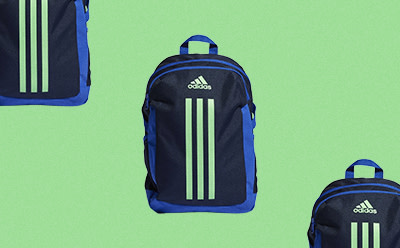 La imagen muestra dos mochilas adidas en azul marino y verde sobre un fondo verde brillante.