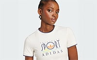 A young woman with dark skin and short hair wearing a white t-shirt with the Adidas logo is standing against a plain white background.