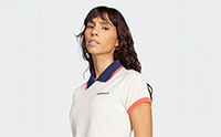 A young woman wearing a white sports jersey with blue and red accents, standing against a plain white background.