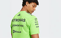 A young man wearing a bright green sports jersey with the text "PETRONAS" prominently displayed on the front, standing against a plain white background.