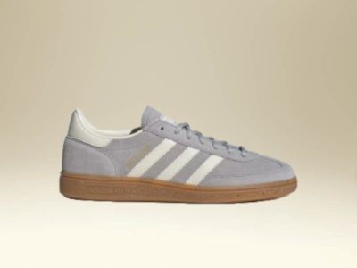 A pair of gray and white sneakers with a gum sole sits on a beige background.