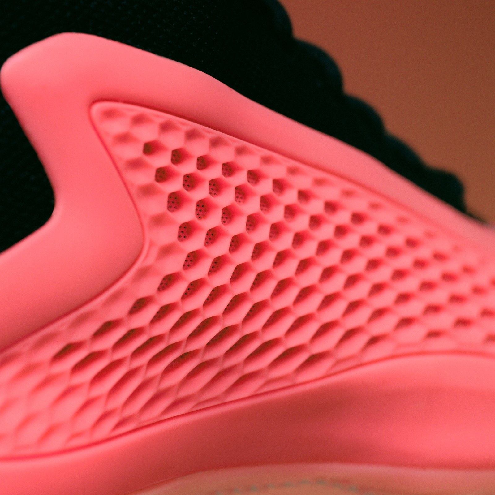 The image shows a close-up view of a textured, pink surface with a honeycomb-like pattern, set against a dark background.