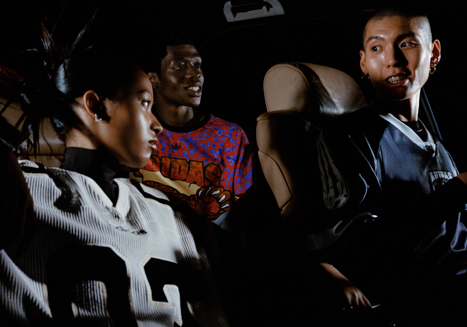 Shot of two adidas models; one male and one female, both wearing adidas football jerseys leaning on a car.