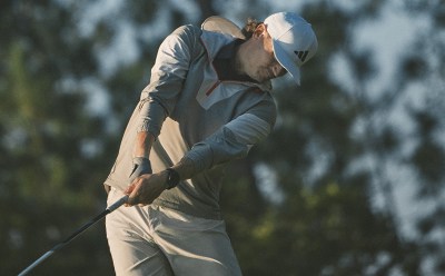 Man swings a golf club in golf jacket