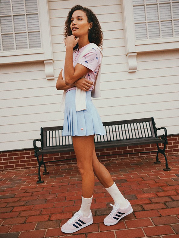 Woman wearing a pink polo and blue golf skirt at a clubhouse.