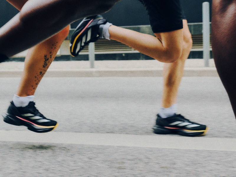 The image shows a person's legs and feet wearing athletic shoes, with the person in a running or sprinting position on what appears to be a track or sports court.