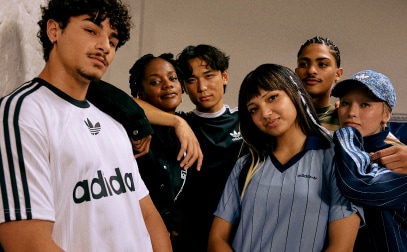 Six people wearing adidas Originals closely huddled in a neutral space and looking straight into the camera.
