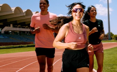 Three people running on a red track.