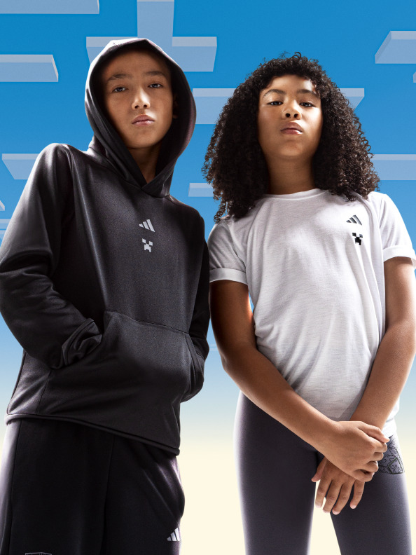 คนหนุ่มสาวสองคน คนหนึ่งสวมสเวตเตอร์มีฮู้ดสีดำและอีกคนหนึ่งเป็นเสื้อยืดสีขาว ยืนตัดกับพื้นหลังสีน้ำเงินสดใสและรูปทรงเรขาคณิต